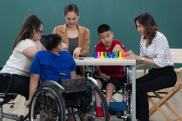 Group of special students in classroom, a down syndrome girl, two handicapped boys and cute Asian teacher playing toy and game together