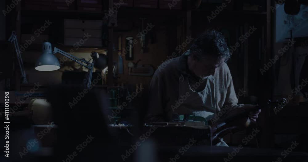 Cinematic shot of experienced master artisan luthier controlling quality of handmade wood violin just made in creative workshop. Concept of spiritual instrument, art, orchestra, passion for music. Cinematic shot of experienced master artisan luthier controlling quality of handmade wood violin just made in creative workshop. Concept of spiritual instrument, art, orchestra, passion for music.