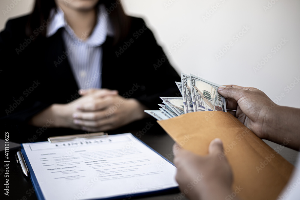 Businesswoman pulls dollar bills out of brown envelopes, hand them over