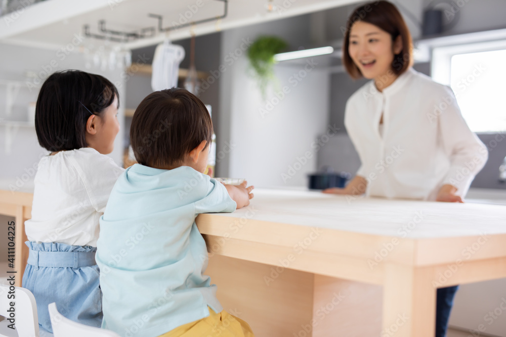 Obraz premium 母親と二人の子供がキッチンのテーブルで過ごしている mother kitchen kids