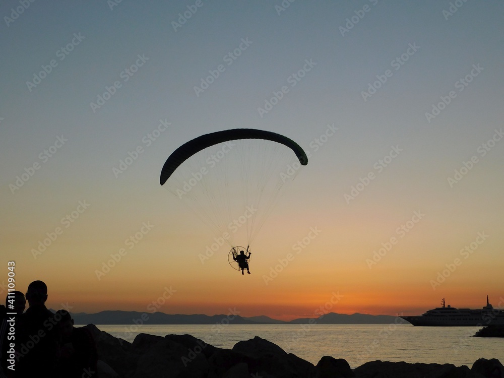 A powered paraglider, flying at sunset, in Glyfada, Greece A powered paraglider, flying at sunset, in Glyfada, Greece