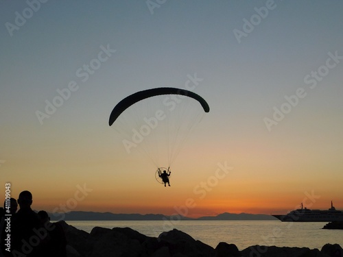 A powered paraglider, flying at sunset, in Glyfada, Greece