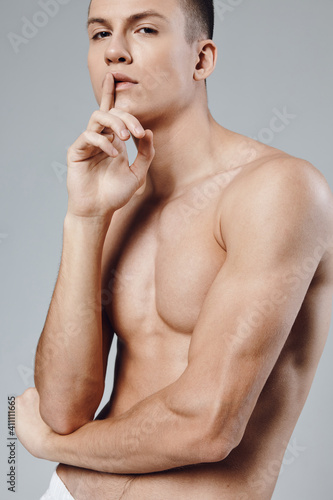 guy with a pumped up press holds a finger near the face on a gray background close-up 