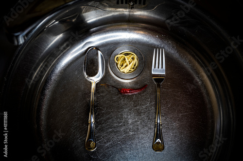 spoon and fork in the sink for washing dishes with spaghetti and pepper