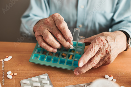 Foto Senior man organizing his medication into pill dispenser