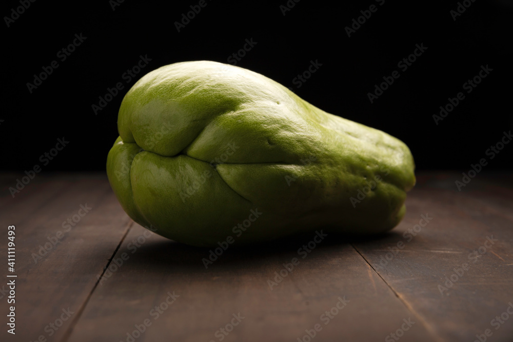 image of a chayote fruit close up on rustic wooden surface and black background image of a chayote fruit close up on rustic wooden surface and black background