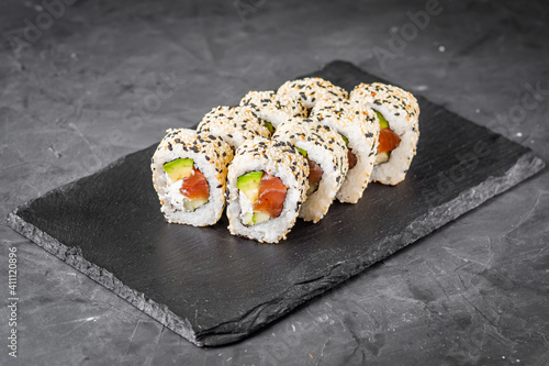 Fotografija appetizing california sushi roll with cheese avocado cucumber and salmon in sesa