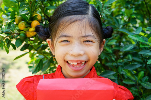 7 years old Happy Asian cute girl wearing Chinese red  dress holding Red envelope or Hong bao or Cheongsam. Chinese new year concept.