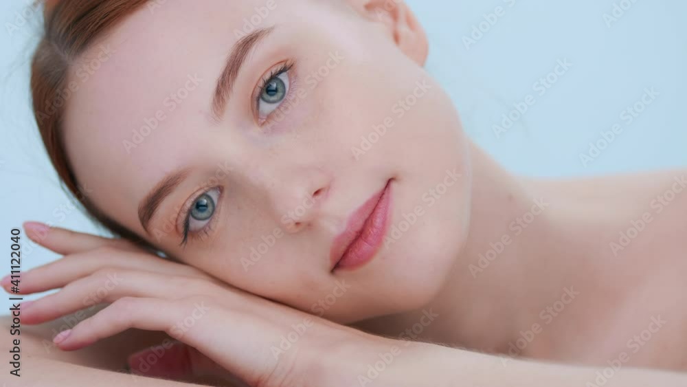 Close-up portrait of young redhead woman with smooth skin tilts her head and slowly lays cheek on her hand | Beauty commercial concept Close-up portrait of young redhead woman with smooth skin tilts her head and slowly lays cheek on her hand | Beauty commercial concept