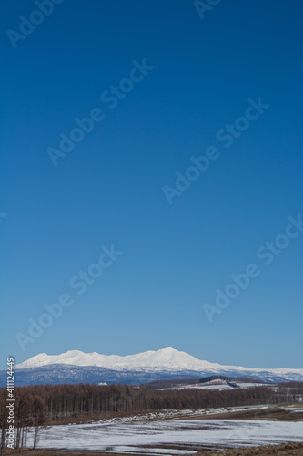 雪が残る春の畑作地帯と雪山　大雪山  © kinpouge