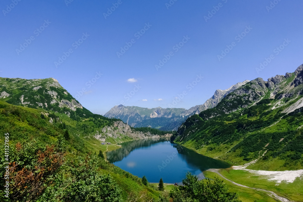 view to a deep blue mountain lake with blue sky while hiking