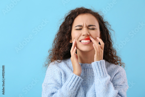 African-American woman with gum inflammation on color background photo