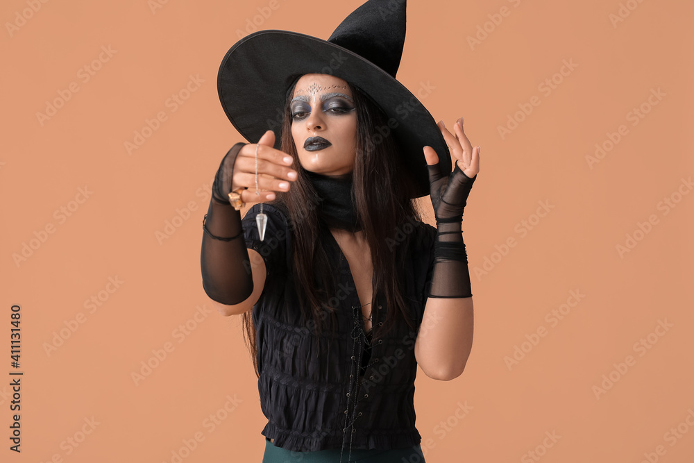 Evil young witch with pendulum on color background Evil young witch with pendulum on color background