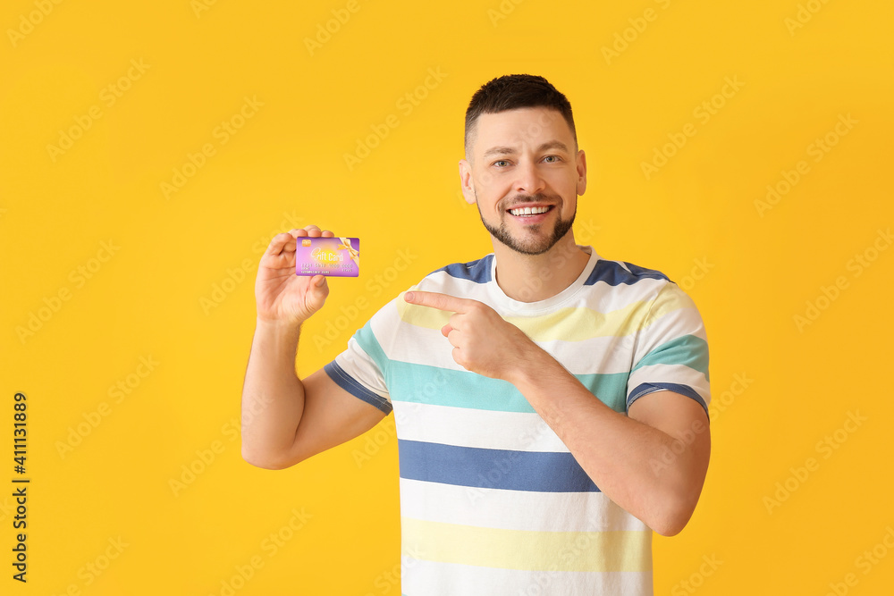 Handsome man with gift card on color background Handsome man with gift card on color background