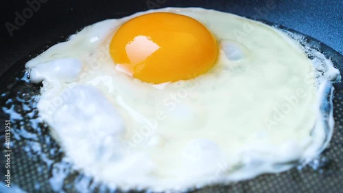 Close up slow motion video for the egg frying in the hot iron panto make fried egg for the breakfast  photo