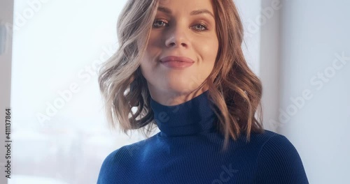 Caucasian woman's portrait. Young caucasian blonde woman in blue dress looks at the camera