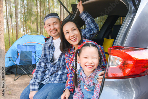Asian family sitting in car trunk going camp on vacations . Family travel by car.