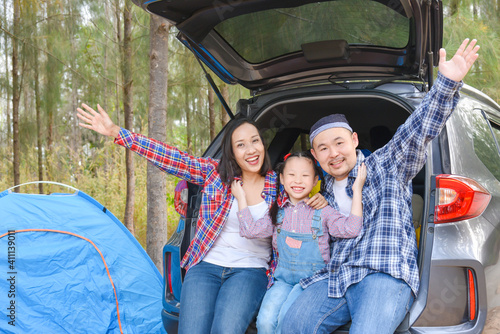 Asian family sitting in car trunk going camp on vacations . Family travel by car.