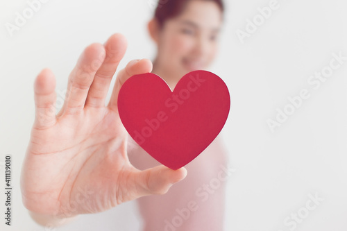 Woman in pink dress shows heart shape in the concept of love and valentine.