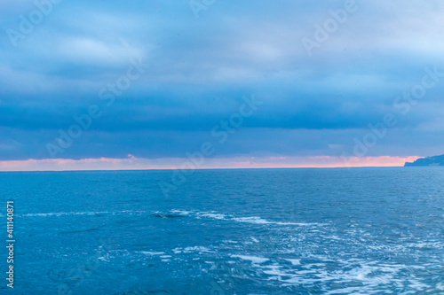 beautiful pink sunset on the blue sea with a beach with waves in good weather on vacation, travel, walk