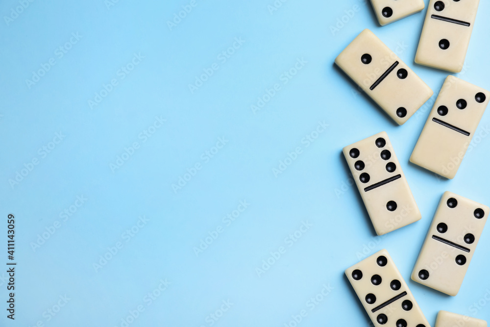 Classic domino tiles on light blue background, flat lay. Space for text Classic domino tiles on light blue background, flat lay. Space for text