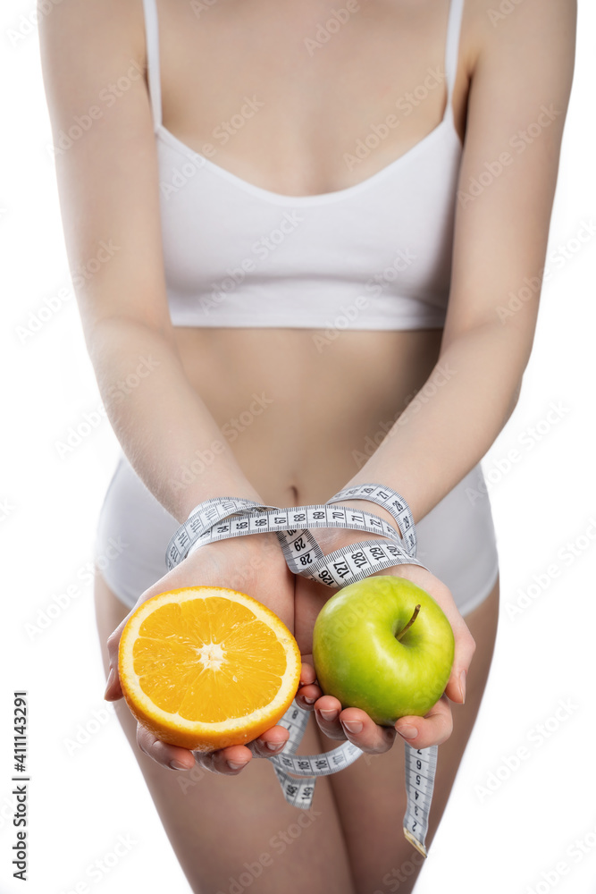 Apple and orange in female hands tied with turquoise measuring tape, isolated on white background Apple and orange in female hands tied with turquoise measuring tape, isolated on white background