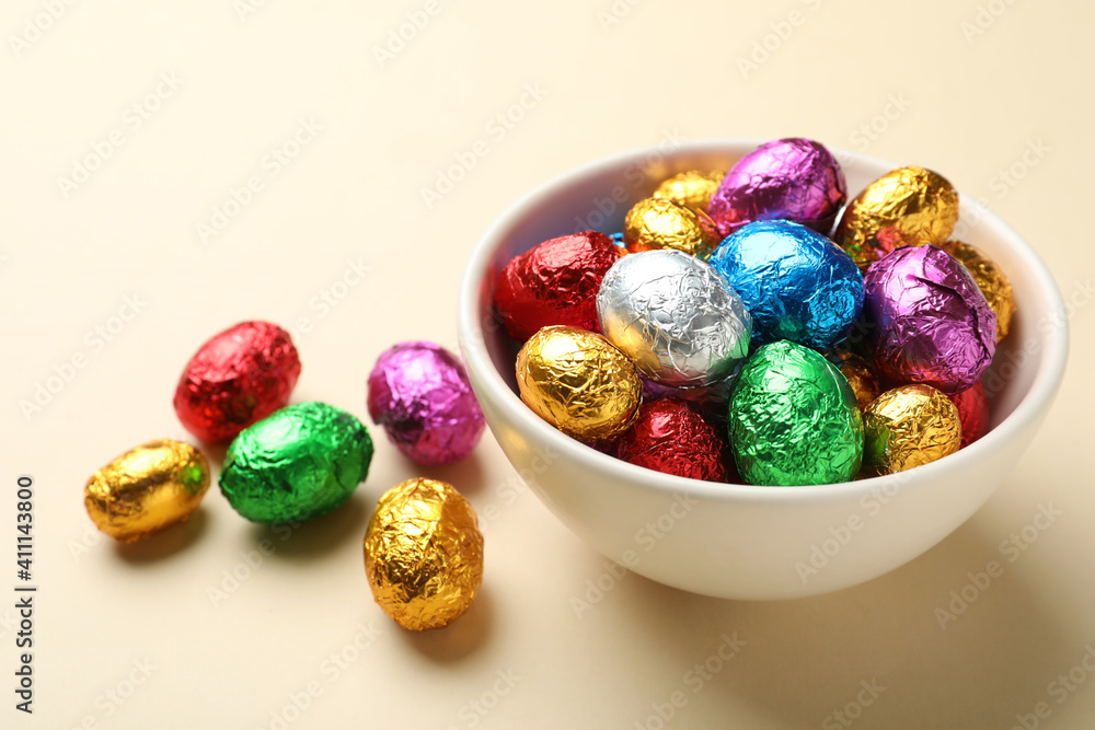 Chocolate eggs wrapped in colorful foil on beige background Chocolate eggs wrapped in colorful foil on beige background