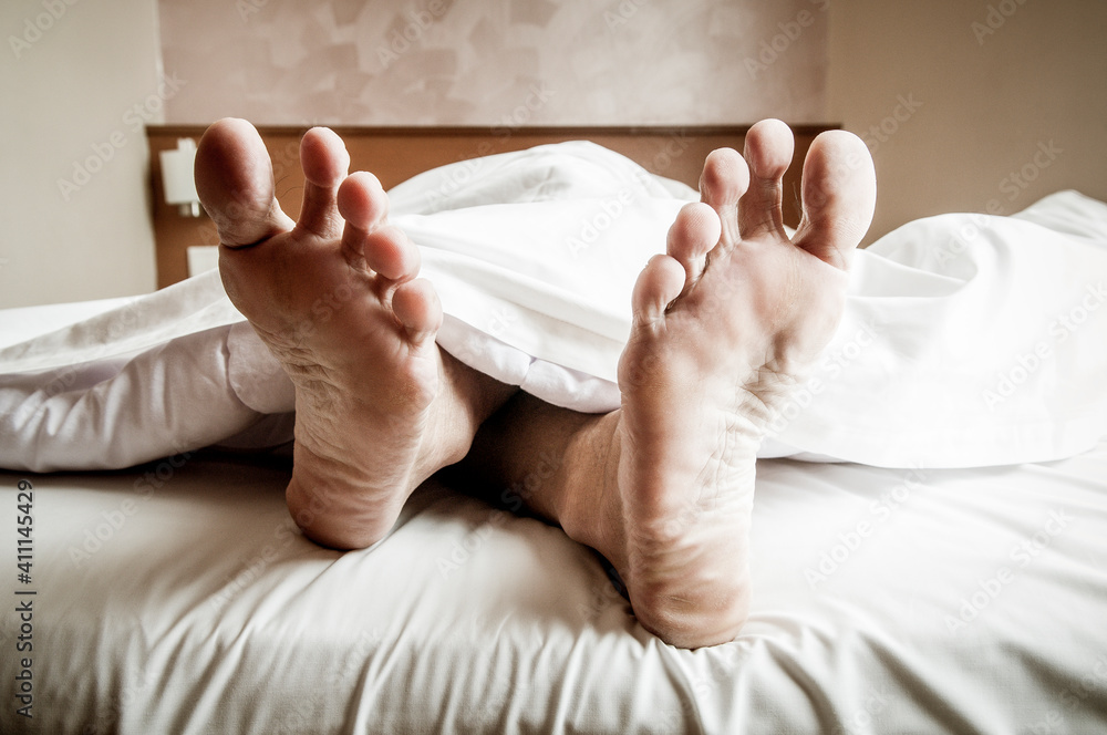 Closeup of exposed feet of a man sleeping in bed Closeup of exposed feet of a man sleeping in bed