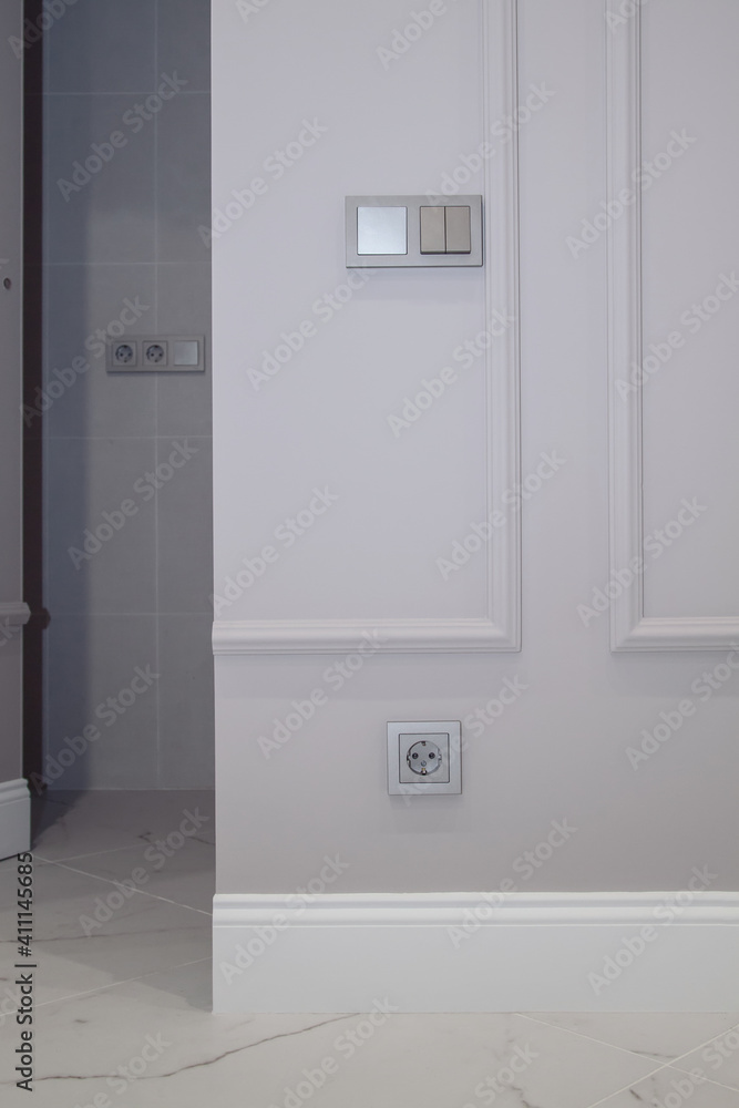 Electrical outlet on brown wall above baseboard and white marble floor. Open invisible hidden door in wall with boiserie in classic interior Electrical outlet on brown wall above baseboard and white marble floor. Open invisible hidden door in wall with boiserie in classic interior