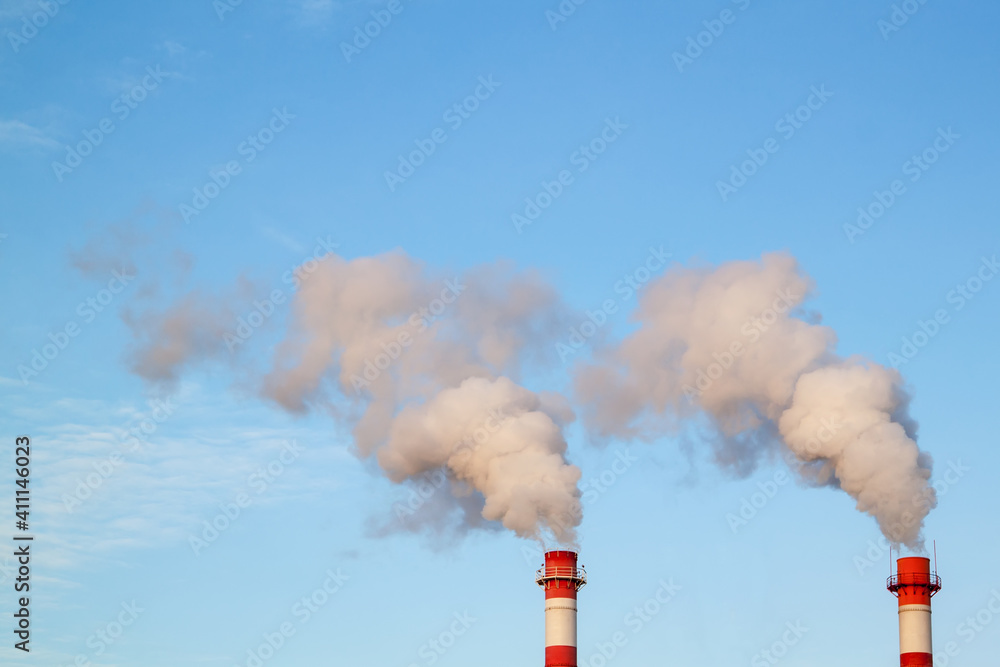 Smoking industrial stacks in thermal power plant emit polluted air into atmosphere in blue sky Smoking industrial stacks in thermal power plant emit polluted air into atmosphere in blue sky