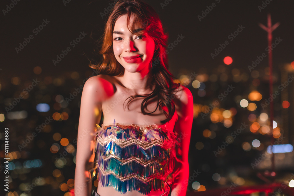 Beautiful young asian brunette woman with white dress joying Christmas or New Year night on a city.Woman holding sparkler against defocused lights, close up.