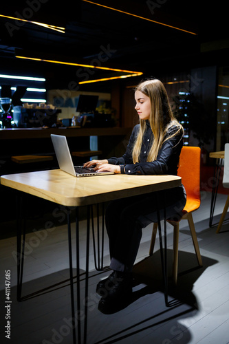 Young woman businessman sitting at a table working with a laptop. Girl manager in the office working on a new project