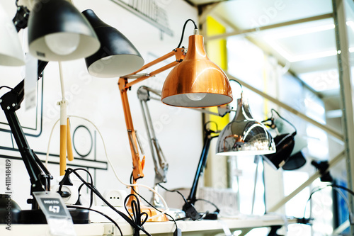 Height-adjustable metal table lamps on the counter in an electrical shop. Close-up