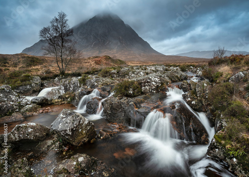 Epic landscape image of Buachaille Etive Mor waterfall in Scottish highlands on a Winter morning with long exposure for smooth flowing water