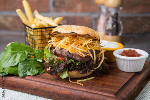 Burger with shoestring fried potatoes and rocket leaves 