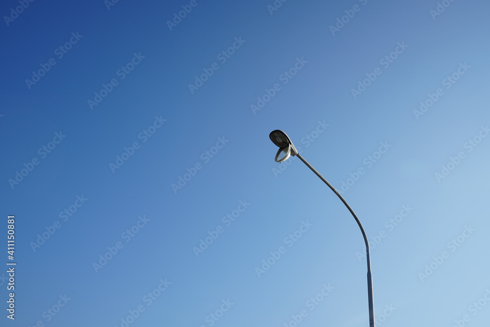 A cover of electric lamp is open and hanging. It's out of order. It represents the maintenance, fixing and repairing the object. Blue sky in the background. A cover of electric lamp is open and hanging. It's out of order. It represents the maintenance, fixing and repairing the object. Blue sky in the background.