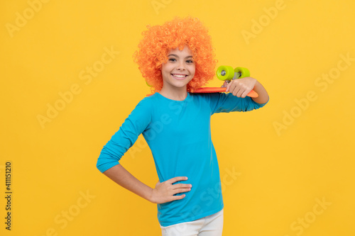 happy teen girl in fancy clown wig hold penny board, childhood