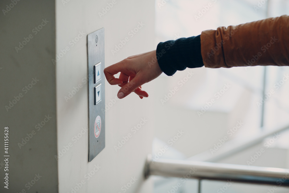 Naklejka premium Close up of forefinger knuckle pressing the button elevator during coronavirus pandemic covid-19 quarantine concept