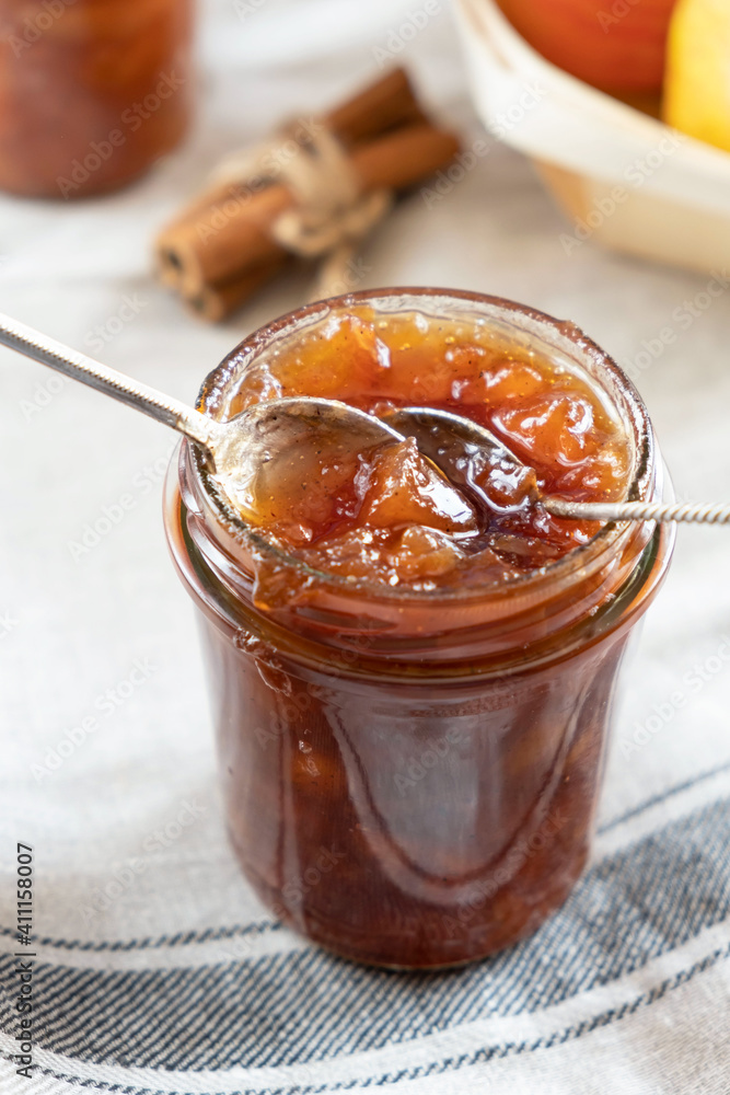 Homemade apple jam marmalade with cloves and cinnamon from organic apples in a transparent glass jar with two vintage retro spoon. Homemade autumn jam preserves. Homemade apple jam marmalade with cloves and cinnamon from organic apples in a transparent glass jar with two vintage retro spoon. Homemade autumn jam preserves.