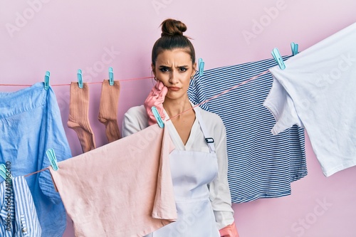 Beautiful brunette young woman washing clothes at clothesline touching mouth with hand with painful expression because of toothache or dental illness on teeth. dentist