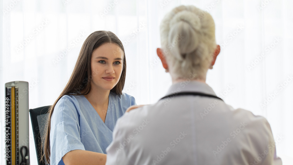 Fototapeta premium A young and beautiful patient talking to a doctor for history taking for a cure.