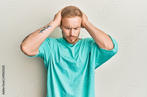 Young caucasian man wearing casual clothes suffering from headache desperate and stressed because pain and migraine. hands on head.