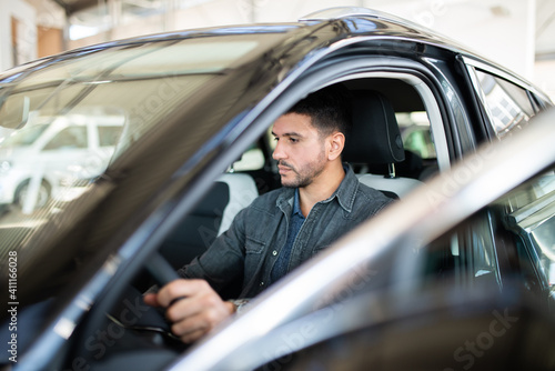 фотографія Smiling man taking taking look to car in showroom