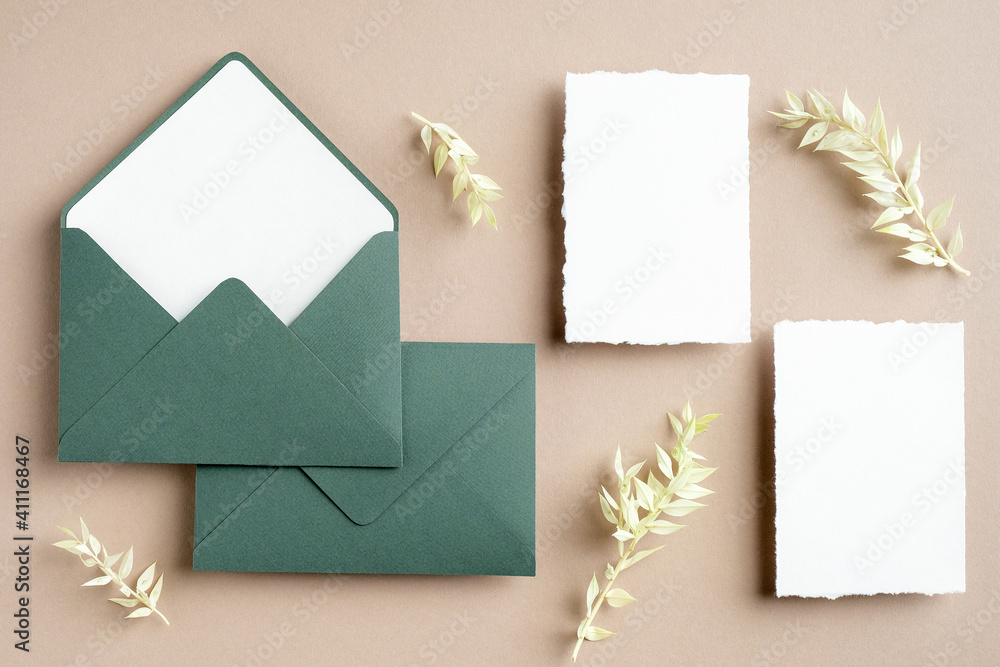 Rustic wedding stationery set top view. Green envelope, blank white paper cards, dried flowers on pastel beige background. Flat lay, top view, copy space. Rustic wedding stationery set top view. Green envelope, blank white paper cards, dried flowers on pastel beige background. Flat lay, top view, copy space.