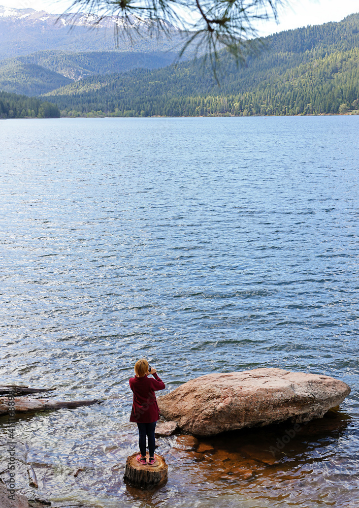 girl photographing lake