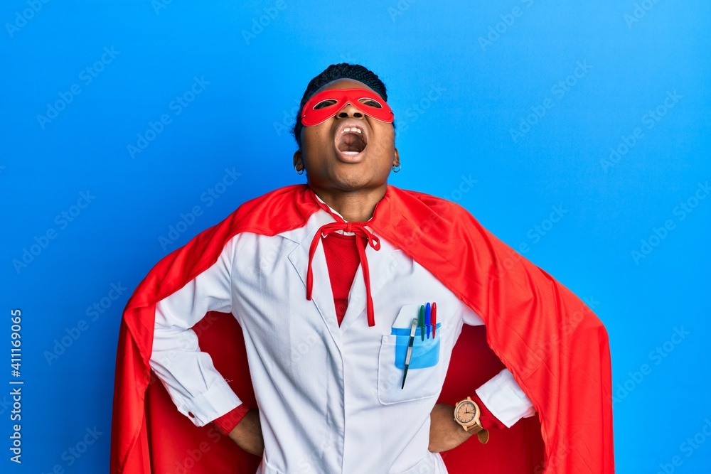 Young african american woman wearing doctor uniform and super hero costume angry and mad screaming frustrated and furious, shouting with anger looking up. Young african american woman wearing doctor uniform and super hero costume angry and mad screaming frustrated and furious, shouting with anger looking up.