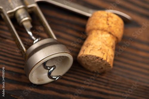 Corkscrew and corks from wine bottles on a wooden table.