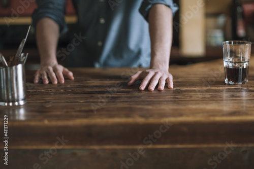 Barman leaning on wooden bar counter