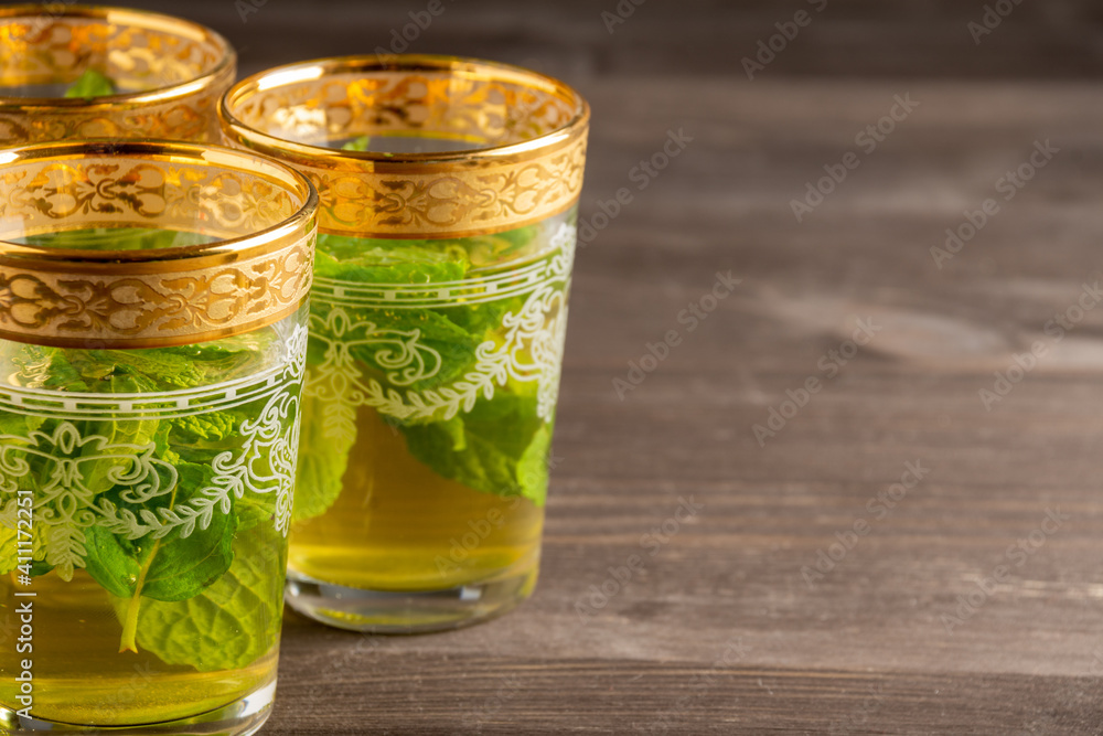 Close-up of three decorated mint tea glasses, selective focus, on wooden table, horizontal, with copy space Close-up of three decorated mint tea glasses, selective focus, on wooden table, horizontal, with copy space