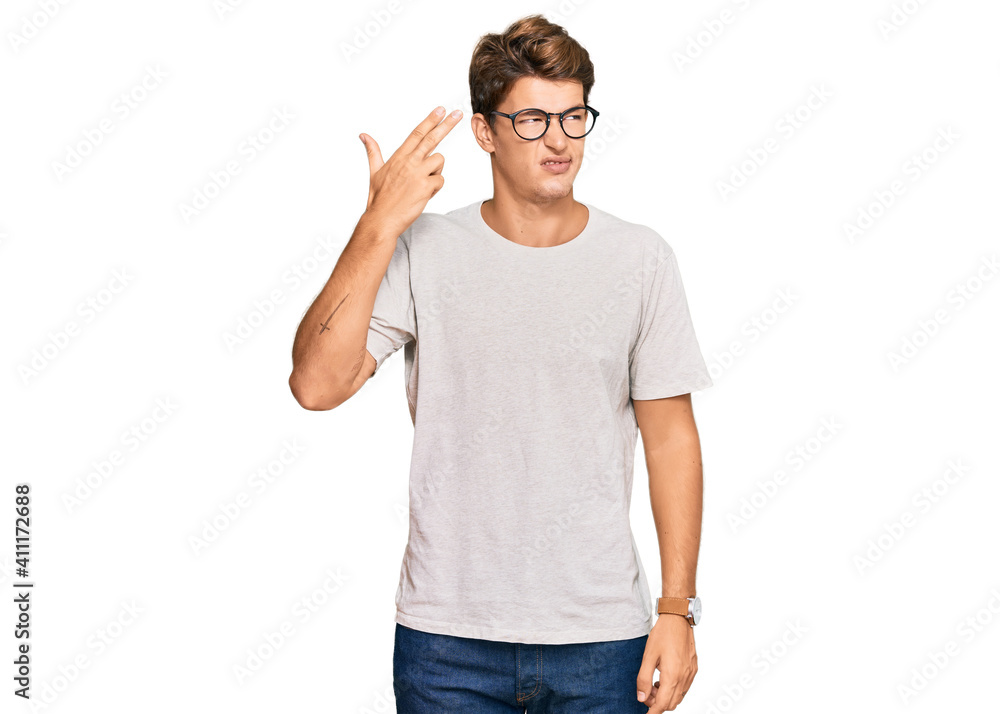 Handsome caucasian man wearing casual clothes and glasses shooting and killing oneself pointing hand and fingers to head like gun, suicide gesture. Handsome caucasian man wearing casual clothes and glasses shooting and killing oneself pointing hand and fingers to head like gun, suicide gesture.
